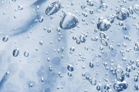 Titelbild für Fest-Flüssig-Trennung. Salzkristalle in hellblauer Flüssigkeit mit Wassertropfen und Luftblasen