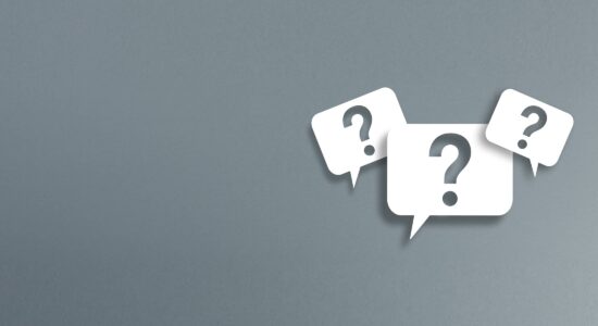 FAQ - Häufig gestellte Fragen - drei weiße Sprechblasen mit einem ausgeschnittenen Fragezeichen auf grauem Grund