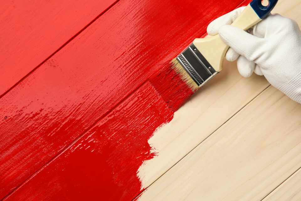 Holz wird mit roter Lackfarbe gestrichen